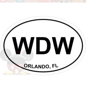 May include: White oval sticker with a black border. The sticker features the letters "WDW" in bold black font, with "ORLANDO, FL" printed below in a smaller black font. The sticker is likely a souvenir.