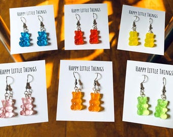 Op de afbeelding: Zes paar gummy bear oorbellen op kaartjes met de tekst "Happy Little Things". De oorbellen zijn in de kleuren blauw, rood, geel, roze, oranje en groen.