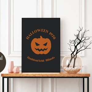 May include: A black and white digital print with the text "Halloween 1978" and a jack-o-lantern with a menacing grin. The text below the jack-o-lantern reads "Haddonfield Illinois".