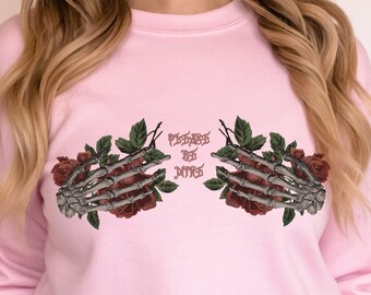 May include: Pink sweatshirt with a graphic of two skeletal hands holding roses and the text "POSSESSED BY DARKNESS".