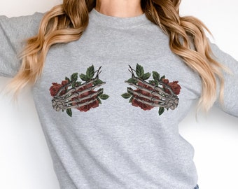 May include: A gray sweatshirt with a graphic of two skeleton hands holding red roses.