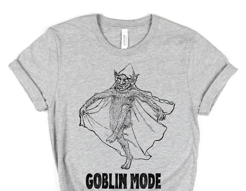 May include: A grey t-shirt featuring a black and white illustration of a goblin wearing a pointed hat and holding a cape. The text "GOBLIN MODE" is printed below the illustration.