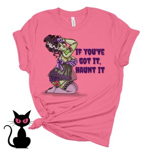 May include: Pink t-shirt with a green and purple illustration of a woman with stitches and the text "If you've got it, haunt it."