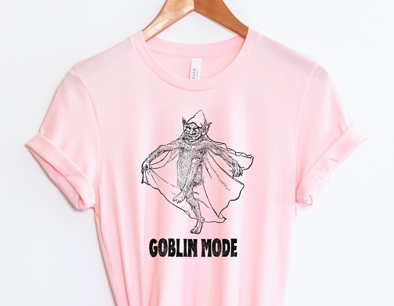 May include: Pink t-shirt featuring a black and white illustration of a goblin wearing a cape. The text "GOBLIN MODE" is printed below the illustration.