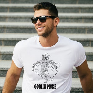May include: A white t-shirt featuring a black and white illustration of a goblin wearing a cape. The text "GOBLIN MODE" is printed beneath the illustration.