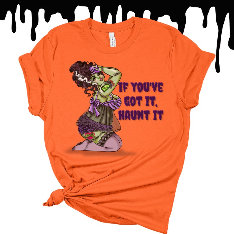 May include: Orange t-shirt with a green and purple cartoon illustration of a woman with stitches and the text "If you've got it, haunt it".