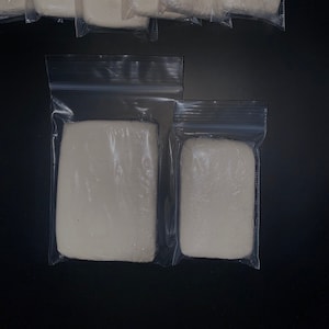 以下が含まれることがあります： 白いモデリングクレイが入った透明なプラスチック袋が複数あります。袋は2列に並べてあり、上の列には6つの袋、下の列には2つの袋があります。