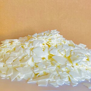 May include: A large pile of white wax flakes, likely for candle making.