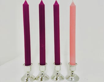 Könnte beinhalten: Vier Kerzenständer mit Kerzen, drei sind lila und eine ist rosa. Die Kerzenständer sind silber.