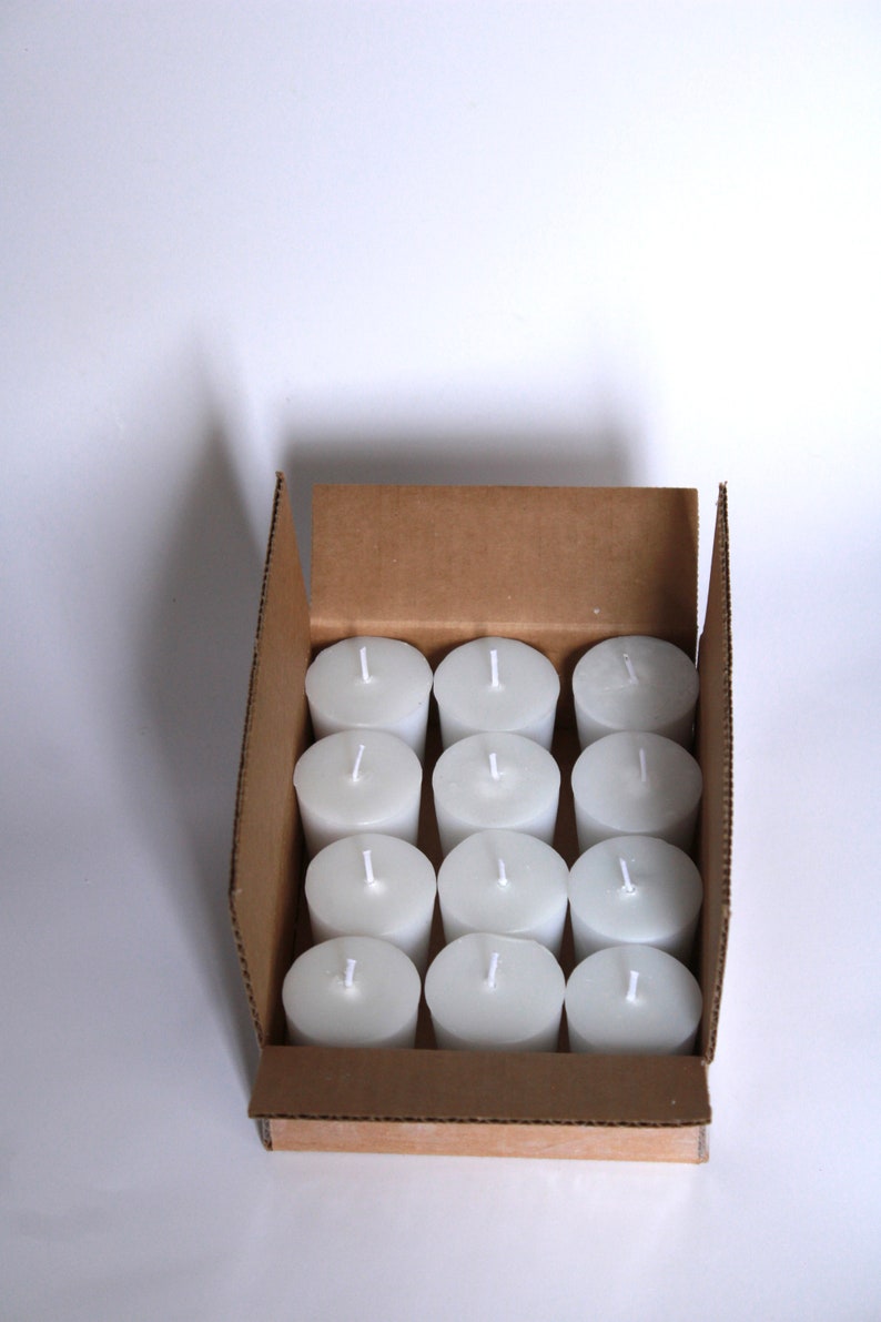 May include: A cardboard box filled with 12 white unscented votive candles.
