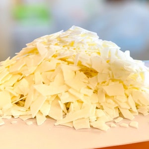 May include: A pile of white wax flakes, likely for candle making, on a white surface.
