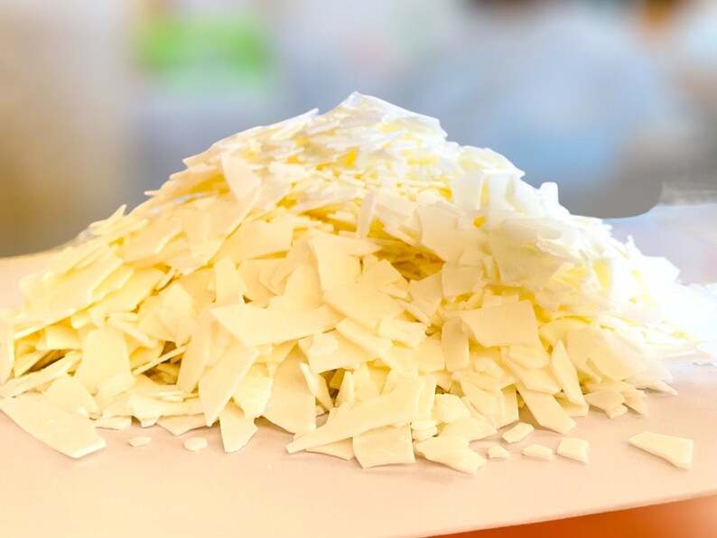 May include: A pile of white wax flakes, likely for candle making, on a white surface.