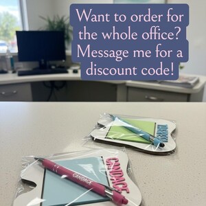 Pode incluir: Dois conjuntos personalizados de bloco de notas e caneta em embalagem transparente. Um conjunto apresenta uma caneta rosa e o nome "Candace" em rosa. O outro conjunto tem uma caneta azul e o nome "There" em azul. A imagem inclui o texto: "Quer encomendar para todo o escrit&oacute;rio? Envie-me uma mensagem para um c&oacute;digo de desconto!"