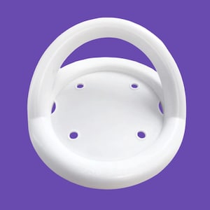 May include: A white, circular shower seat with a curved handle. The seat has four evenly spaced holes and is set against a purple background. The handle is arched, providing support for the user.