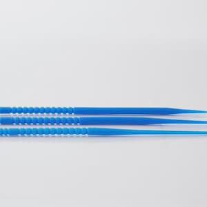May include: Three blue dental picks of varying lengths are arranged horizontally against a white background. The picks have textured handles with white accents and tapered tips, suggesting a dental hygiene product.