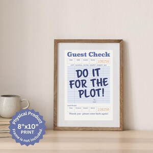 以下が含まれることがあります： 白い背景に青い文字で「Do it for the plot!」と書かれた、ゲストチェックの8x10インチの額装プリント。チェックは青と白のグリッドパターンになっています。プリントは茶色のフレームに入っています。