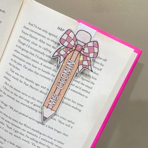K&ouml;nnte beinhalten: Ein rosa Bleistift mit dem Text "Ms. Cronin" darauf, verziert mit einer rosa und wei&szlig;en karierten Schleife mit einem goldenen Stern. Der Bleistift ist ein Lesezeichen.