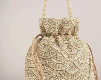 May include: A cream-coloured beaded drawstring bag with a pearl chain handle and tassel. The bag is decorated with a pattern of white beads.