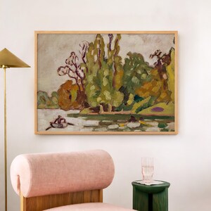 May include: A framed landscape painting depicts a river scene with trees in shades of green, yellow, and brown. Two figures are in a small boat on the water. The artwork is displayed on a white wall above a pink chair and a green side table.