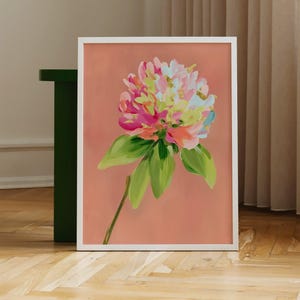 May include: A framed painting of a pink, white, and green flower with a peach background.