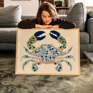 May include: A framed print of a blue and yellow crab with a white, pink, and blue spotted body. The crab is on a white background.
