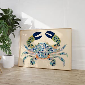 May include: A framed print of a blue and green crab with a white background. The crab has a spotted shell and yellow claws.