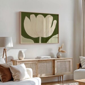 Peut inclure: Une impression encadr&eacute;e d'un tulipe blanc sur fond vert. L'impression est accroch&eacute;e &agrave; un mur blanc au-dessus d'une armoire en bois avec des portes en rotin tiss&eacute;.