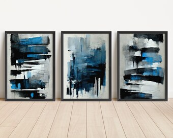 May include: Three framed abstract paintings with a blue, black and white colour scheme. The paintings are in black frames and are hanging on a white wall.