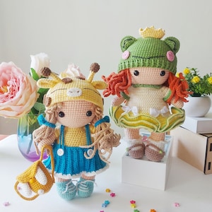 Peut inclure: Deux poupées en crochet, l'une habillée en girafe et l'autre en grenouille. La poupée girafe porte une robe jaune et bleue et porte un petit sac en crochet. La poupée grenouille porte une robe verte et jaune avec une couronne.