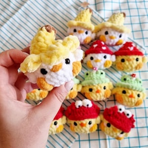 May include: A collection of crocheted chick ornaments with various toppings, including a banana, a mushroom, and a green hat. The chicks are all white with yellow beaks and black eyes.