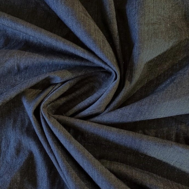 May include: A close-up of a dark blue denim fabric, showing the texture and weave of the material.