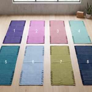 Puede incluir: Ocho alfombras de pasillo rectangulares dispuestas en dos filas, cada una con un color sólido y rayas horizontales texturizadas en los extremos. Los colores incluyen morado, rosa, rosa viejo, menta, turquesa, azul claro, verde oliva y azul marino, numerados del uno al ocho.