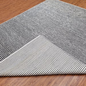 May include: A black and white striped rug with a geometric design. The rug is made of a soft, woven material and has a contemporary style.