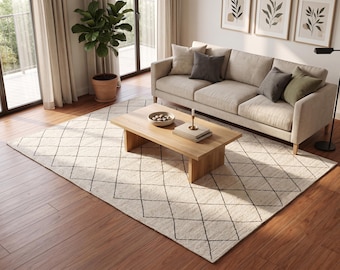 May include: A rectangular area rug featuring a cream-colored base with a thin, dark-colored diamond grid pattern. The rug is positioned on a wooden floor, extending underneath a light-colored sofa and a wooden coffee table in a living room setting.