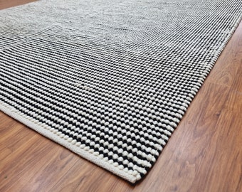 Puede incluir: Una alfombra con estampado en blanco y negro con un borde blanco. La alfombra está hecha de un material grueso y texturizado.