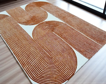May include: A rectangular area rug featuring a cream-colored base with a raised, textured pattern of burnt orange lines. The design consists of large, interconnected U-shaped and curved geometric forms created by dense, parallel tufted yarn.