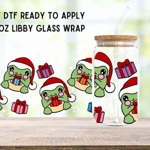May include: A clear glass 16 oz Libby glass wrap with a white background and a design of green frogs wearing Santa hats and holding presents. The text "UV DTF READY TO APPLY" is at the top of the image.