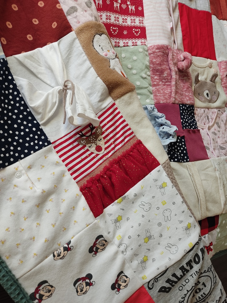 Puede incluir: Un edred&oacute;n de patchwork compuesto por varios retazos de tela, incluyendo blanco, rojo y azul marino. El edred&oacute;n presenta patrones como lunares, rayas y personajes de dibujos animados. Algunas secciones tienen elementos decorativos como volantes y dise&ntilde;os bordados.