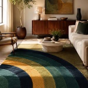 May include: A rectangular area rug featuring a large, concentric semi-circular arch pattern. The design consists of thick, textured bands in shades of deep navy blue, forest green, olive green, and mustard yellow, creating a bold, layered visual effect.