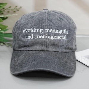 Pode incluir: Boné de beisebol cinza com o texto bordado em branco "avoiding meningitis and meningeneneral". O boné é feito de um tecido macio e desgastado e tem uma aba curva. Um acessório casual.