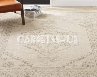 May include: A rectangular area rug in a light beige tone featuring a dark gray geometric and floral pattern. The rug displays a central diamond motif surrounded by a detailed border. The text CARPETSSHUB is overlaid in white across the center.