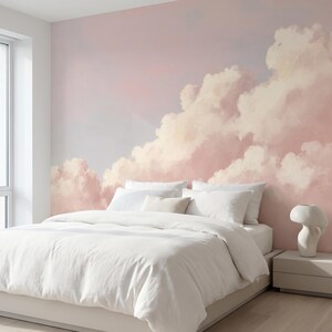 May include: A bedroom with a large cloud mural on the wall. The mural features a pink and white cloudscape. A white bed with white bedding is in front of the mural. A white bedside table with a white decorative vase is next to the bed.