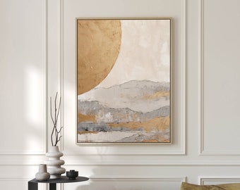 May include: A framed abstract painting with a gold and white color scheme. The painting depicts a large, golden circle partially obscured by a series of layered, gray and white mountains. The painting is hanging on a white wall above a black side table.
