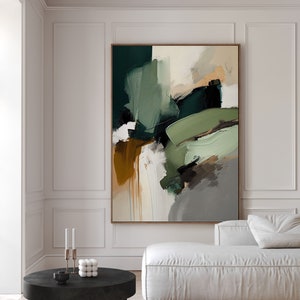 Può includere: Dipinto astratto con pennellate verdi, marroni e bianche su una tela. Il dipinto è appeso a una parete bianca in un soggiorno moderno con un divano bianco e un tavolino da caffè nero.