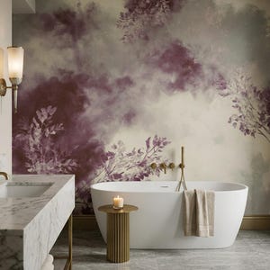 May include: A bathroom featuring a white freestanding bathtub, a marble vanity with a gold faucet, and a wall mural with a watercolor-style floral pattern in shades of deep purple, cream, and muted green, accented by gold wall sconces.
