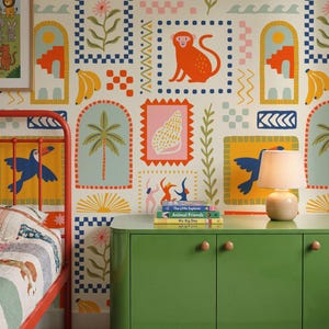 May include: Wallpaper featuring a repeating pattern of colorful illustrations including monkeys, seashells, palm trees, toucans, bananas, and dancing figures on a cream background, with a red metal bed frame and a green cabinet in the foreground.