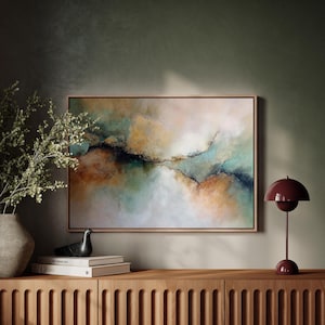 May include: Abstract landscape painting in a wooden frame, with teal, gold, and white hues. The artwork hangs above a wooden cabinet, complemented by a decorative lamp and vase, creating a stylish interior.
