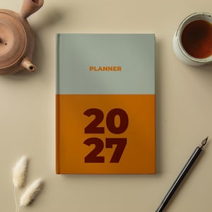 Peut inclure: Un agenda rectangulaire avec une couverture bicolore comprenant une moitié supérieure gris clair avec le mot PLANNER en orange et une moitié inférieure orange foncé avec les grands chiffres marron foncé 20 27 imprimés au centre.