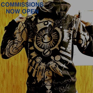 Peut inclure: Un sweat à capuche noir et gris avec un motif artistique détaillé au dos. Le motif présente des motifs et des formes complexes. Le texte "COMMISSIONS NOW OPEN" est affiché en bleu en haut.