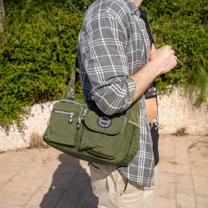 May include: A green nylon crossbody bag with multiple pockets and zippers. The bag has a black logo that says "Larch Everyday Fashion Bag".